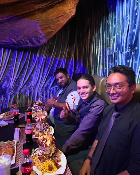 Grupo de amigos reunidos alrededor de una hamburguesa gigante en el salón del restaurante