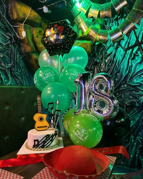 Mesa decorada con globos verdes y torta para una celebración de 18 años en el restaurante