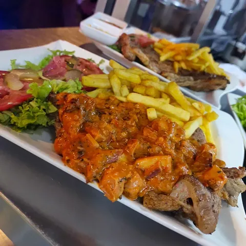 Churrasco a la plancha con papas a la francesa y ensalada fresca servido en plato blanco