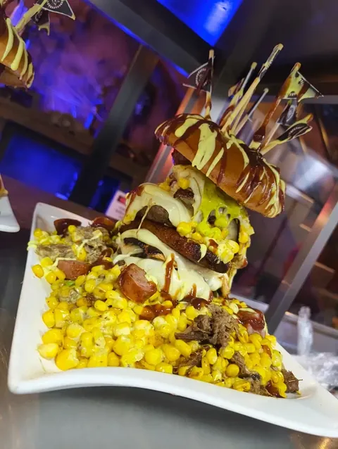 Mazorcada servida en torre con maíz tierno, carne, queso fundido y banderines piratas