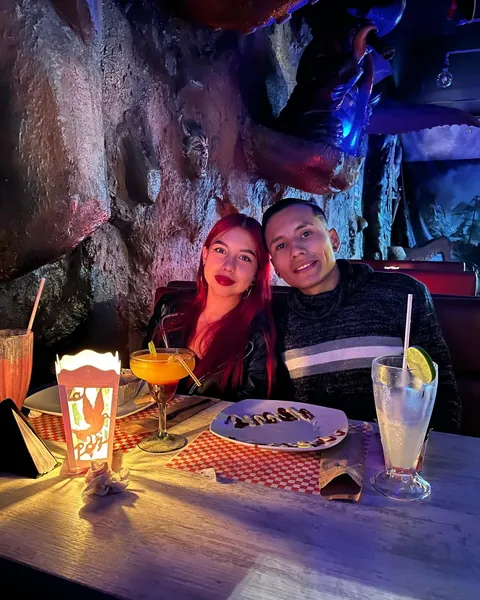 Pareja compartiendo cócteles y una entrada en una mesa de mantel a cuadros del restaurante